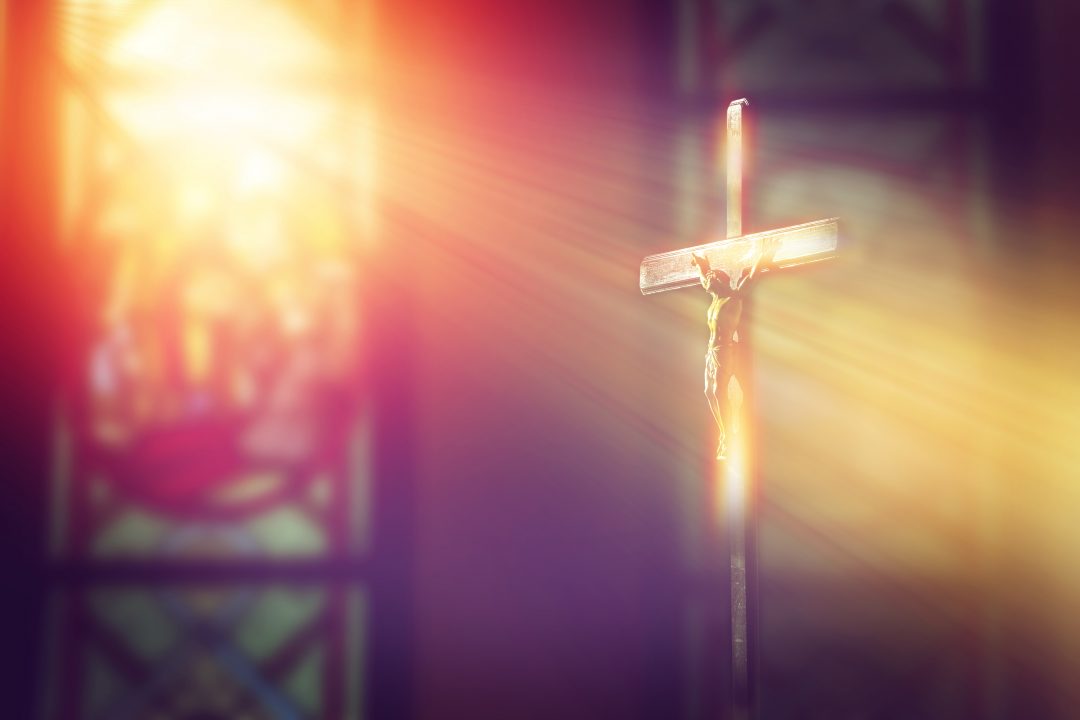 Crucifix with ray of light from stained glass